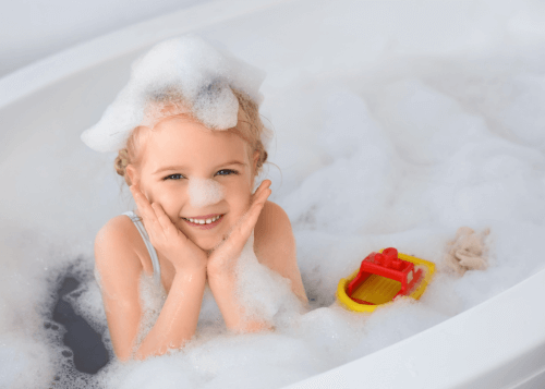 Enfant jouant dans son bain avec des savons colorés en forme de cupcake, illustrant le danger de confusion entre produits cosmétiques et gâteaux.